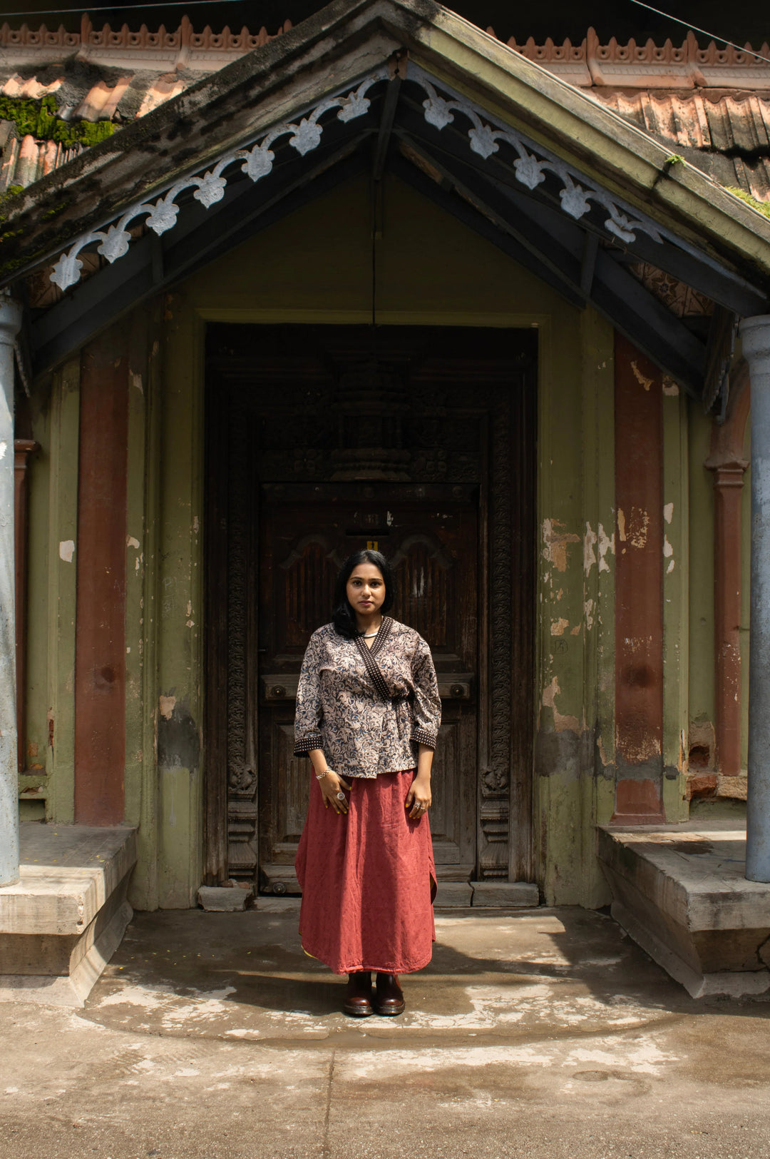 Model wearing a kalamkari printed wrap style, short top in cotton with a red skirt. 