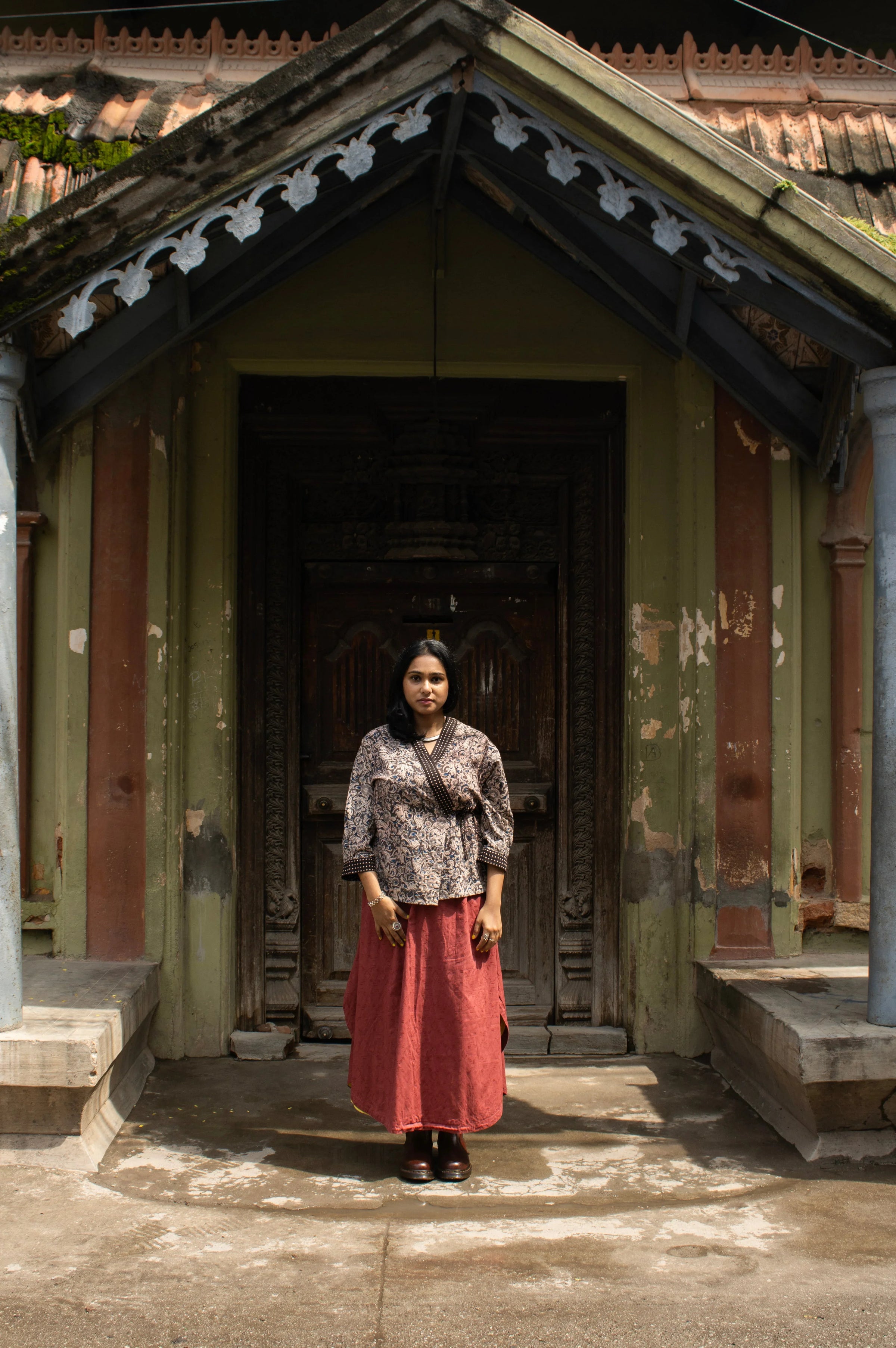 Model wearing a kalamkari printed wrap style, short top in cotton with a red skirt. 